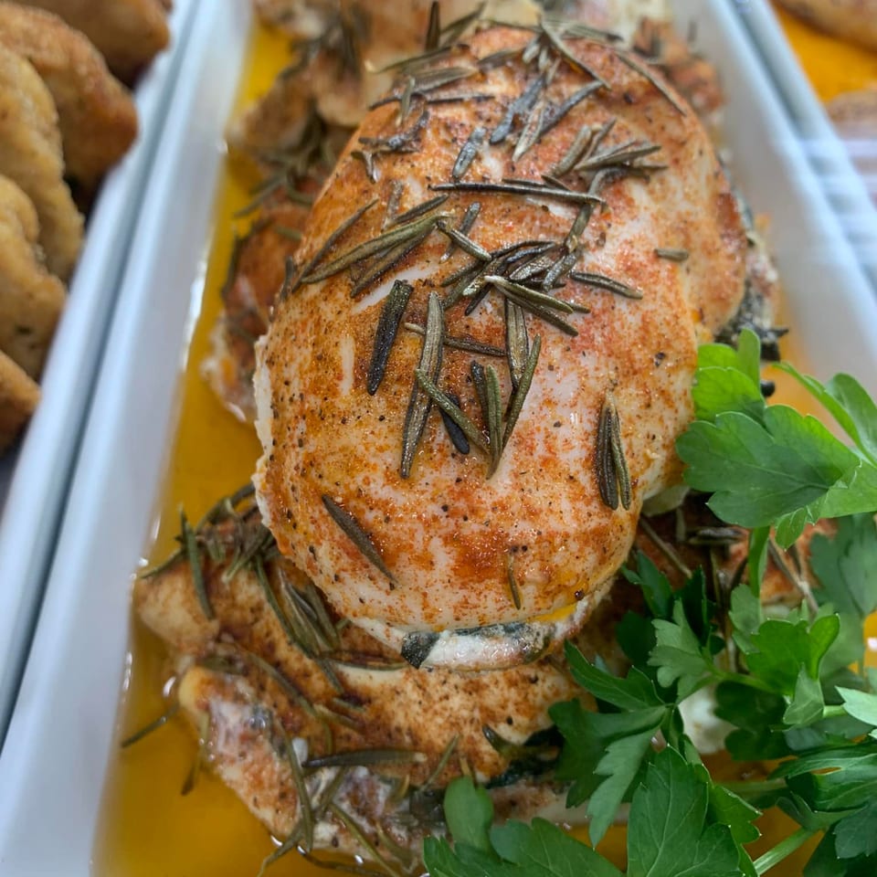 Rosemary chicken breasts with paprika and parsley in a white serving dish at Parma Market & Bakery.