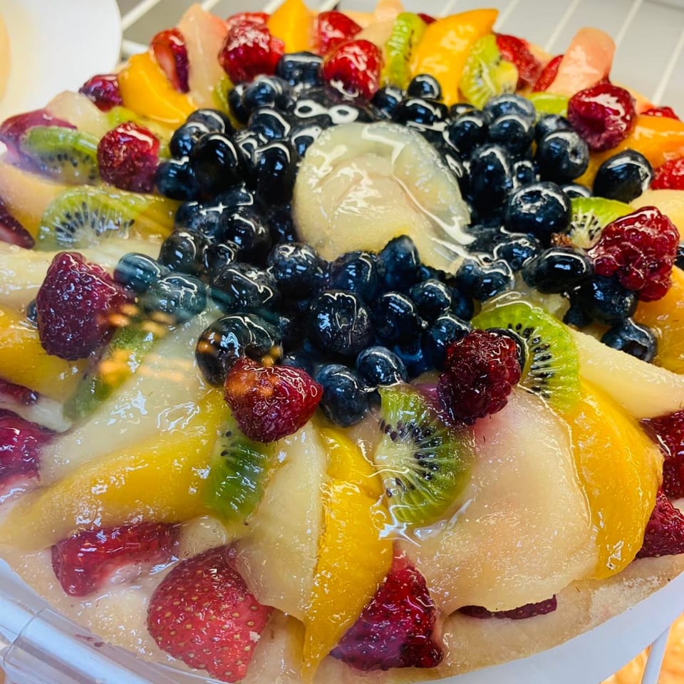 Close-up of a vibrant fruit tart from Parma Market & Bakery, featuring blueberries, raspberries, kiwi, and peaches.